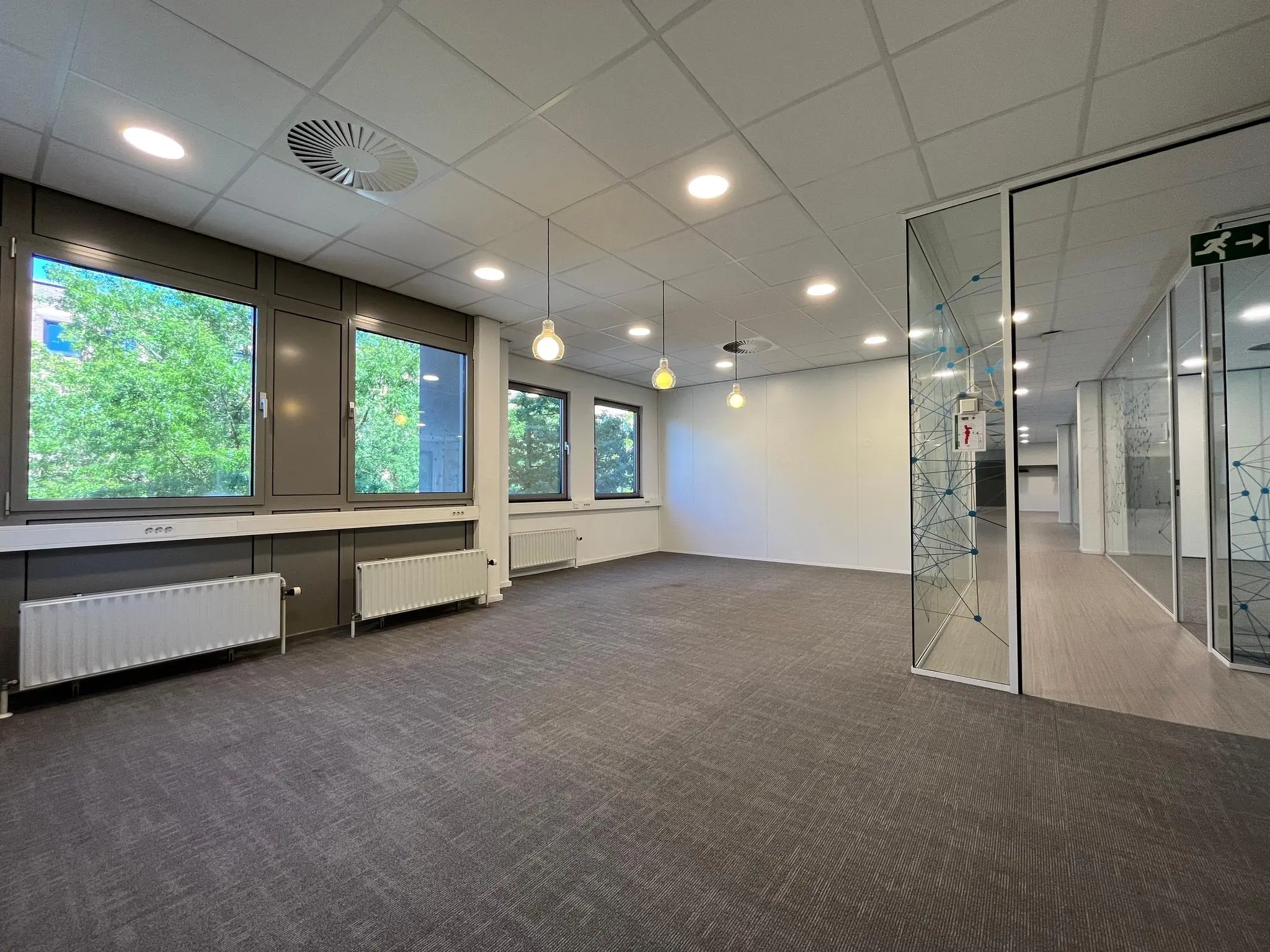 Moderne, lege kantoorruimte aan de Barchman Wuytierslaan met grote ramen, glazen wanden en grijze vloerbedekking.